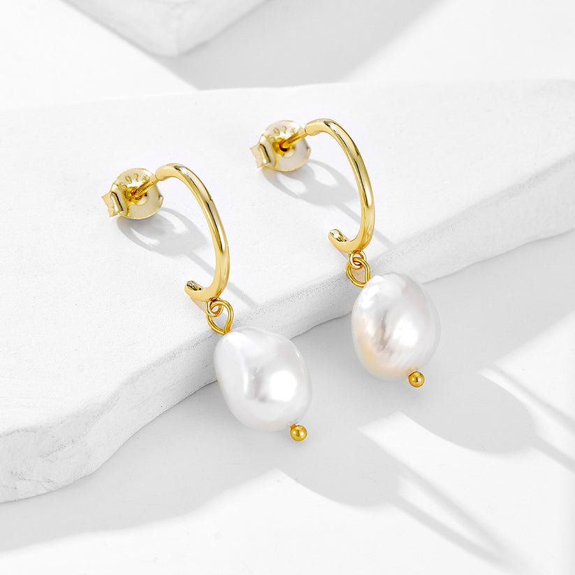 Planderful irregular freshwater pearl earrings with gold-tone hoops on white sculptural surfaces