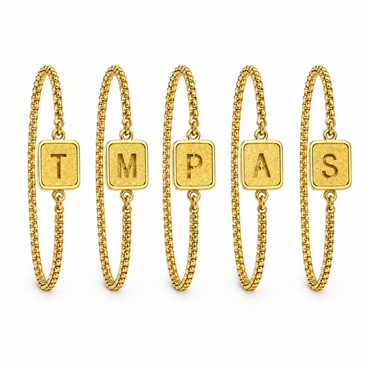 Gold initial chain bracelets on a white background